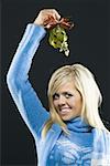 Portrait of a young woman holding mistletoe above her head