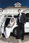 Portrait of a groom standing with a bride sitting in a car