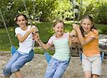 Portrait de trois jeunes filles, assis sur les balançoires