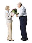 Older man giving wife bouquet of pink roses