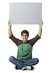 Portrait of a young man holding up a blank sign