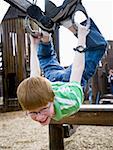 Boy hanging on climbing set at playground outdoors