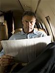 Portrait of a businessman holding a newspaper in an airplane