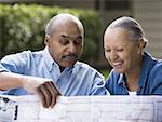 Mature man and woman looking at map outdoors smiling