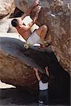 High angle view of a man rock climbing and a child reaching up from below