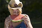 Gros plan d'une jeune femme de mordre un morceau de melon d'eau