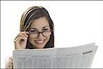 Gros plan d'une jeune femme lisant un journal et souriant