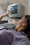 Pregnant woman lying on a hospital bed looking at her ultrasound result