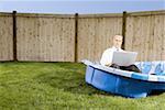 Mitte erwachsener Mann arbeitet auf einem Laptop sitzt in ein Planschbecken