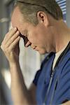 Close-up of a male doctor with his hand on his forehead