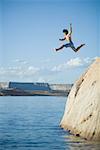 Low angle view of a young man jumping into a lake