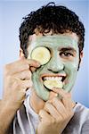 Man with facial mask and cucumber slices