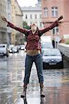 Teenage girl standing on a wet street and looking up
