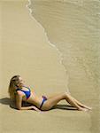 Erhöhte Ansicht einer jungen Frau, die am Strand liegen