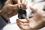 Close-up of a person giving a car key to another person