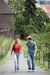 Teenage couple holding hands and walking together on a path