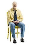 Portrait d'un homme senior assis sur une chaise et souriant