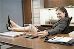 Profile of a businesswoman resting her legs on the table and smiling