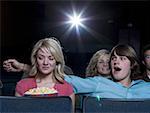 Junge erreichen Arm heraus hinter Mädchen mit Popcorn im Kino
