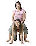 Portrait of a teenage girl sitting on her sister's back