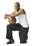 Portrait d'un jeune homme à genoux avec un ballon de basket