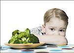 Close-up of a boy looking at broccoli on a plate