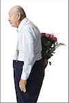 Older man with bouquet of pink roses behind back