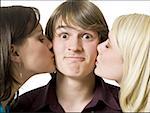 Two girls kissing boy on cheeks