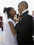 Profile of a newlywed couple holding hands and looking at each other