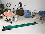 High angle view of a senior man playing golf in the living room