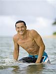 Portrait d'un jeune homme assis sur une planche de surf