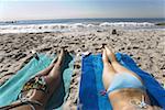 Rear view of two young women sunbathing on the beach