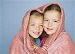 Portrait of two girls under a blanket and smiling