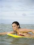Profile of a teenage girl floating on a boogie board in the sea