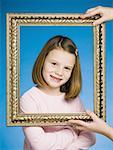 Girl looking through picture frame smiling