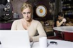 Junge Frau auf einem Laptop in einem Café arbeiten