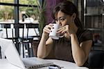 Jeune femme à boire du café et de travailler sur un ordinateur portable