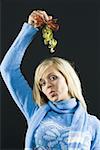 Portrait of a young woman holding mistletoe above her head and puckering lips