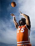 Basketball player with an afro in orange uniform taking shot