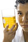 Portrait of a young woman showing a measuring beaker with liquid