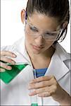 Close-up of a female technician pouring liquid from a beaker into a test tube