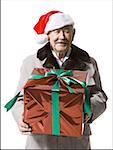 Older man in Santa hat holding a Christmas present