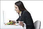 Profile of a businesswoman eating and using a laptop