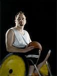 Close-up of a young man sitting in a wheelchair holding a basketball