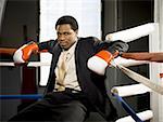 Portrait of a businessman sitting in a boxing ring