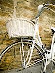 Bicycle with basket leaning on brick wall
