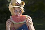 Portrait d'une jeune femme de mordre un morceau de melon d'eau