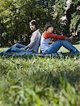 Teenager paar sitzen Rücken an Rücken im park