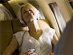 Une femme d'affaires, écouter de la musique sur le casque dans un avion