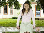 Portrait of a girl sitting on a wooden fence